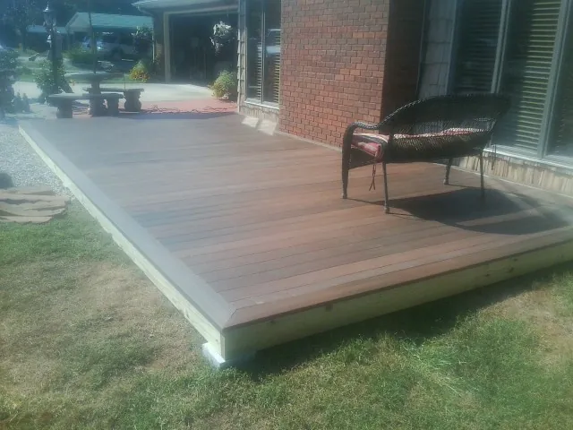 New wood deck and wicker chair beside a brick house in Greensboro